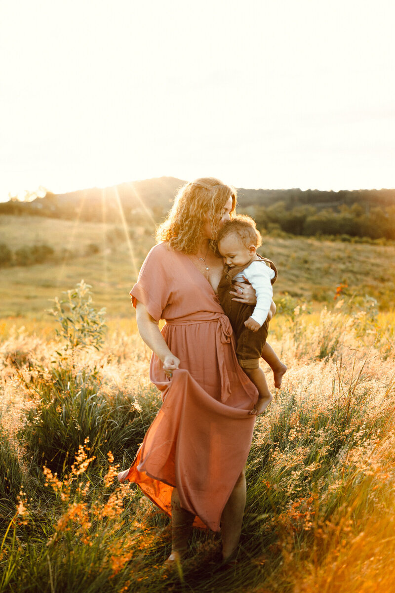 Mother standing in Brisbane Golden fields, holding her son and giving him lots of love in the golden light