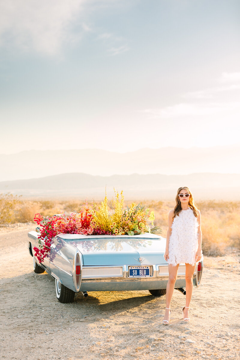woman next to vintage blue car with florals in california