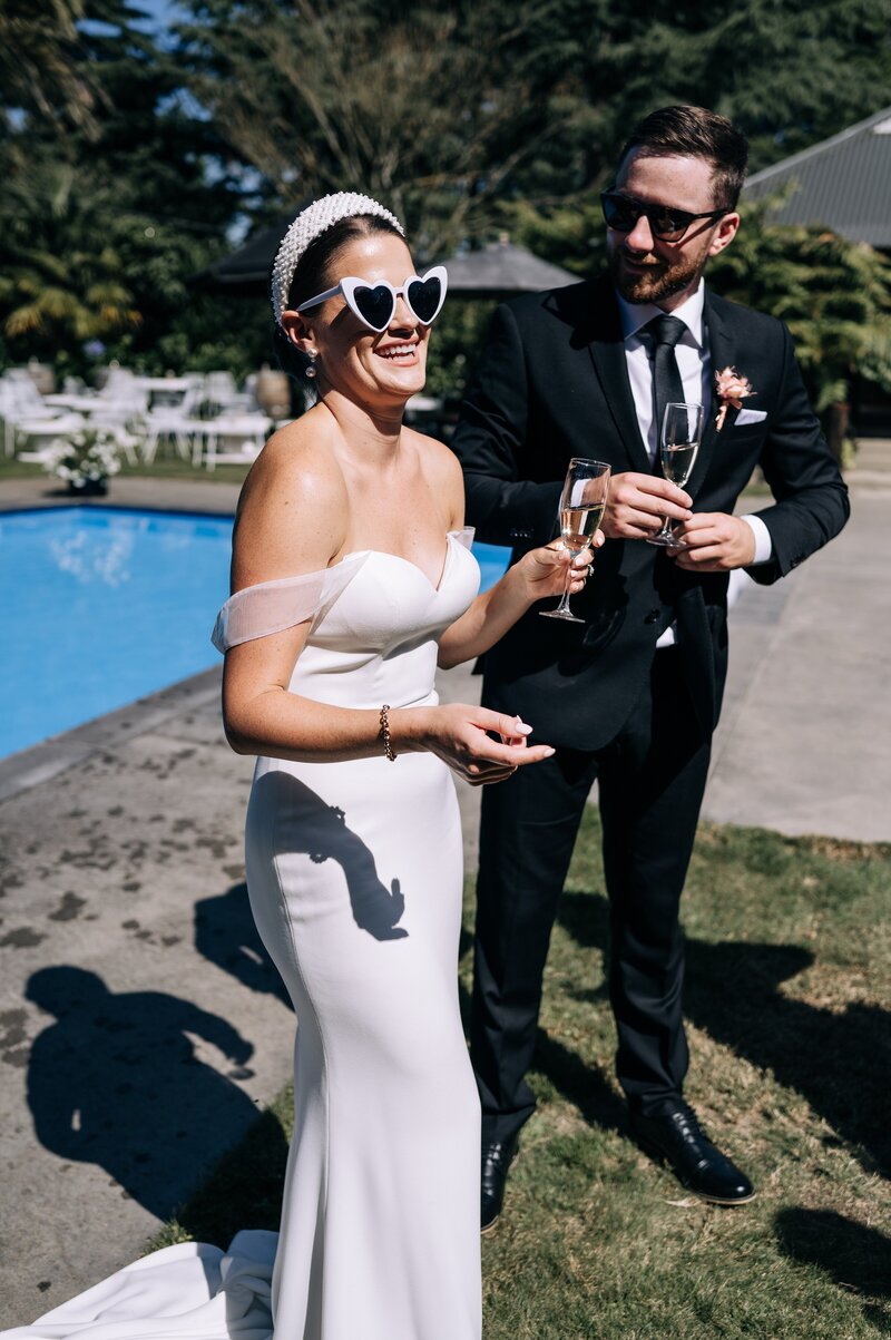 bride in beaded headband and trish peng dress laughs beside the pool at her backyard wedding in christchurch