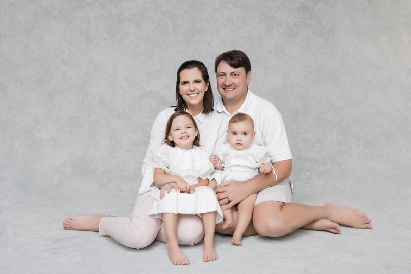 Two parents sitting on the ground with small children in each of their laps