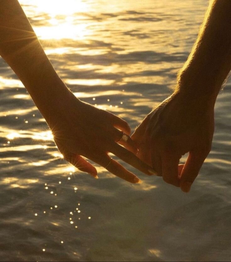 Close-up of couple holding hands at the beach, symbolizing secure attachment