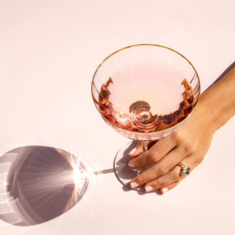 Woman hand holding pink cocktail glass