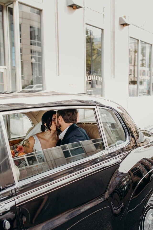 Bride and groom kiss in classic car