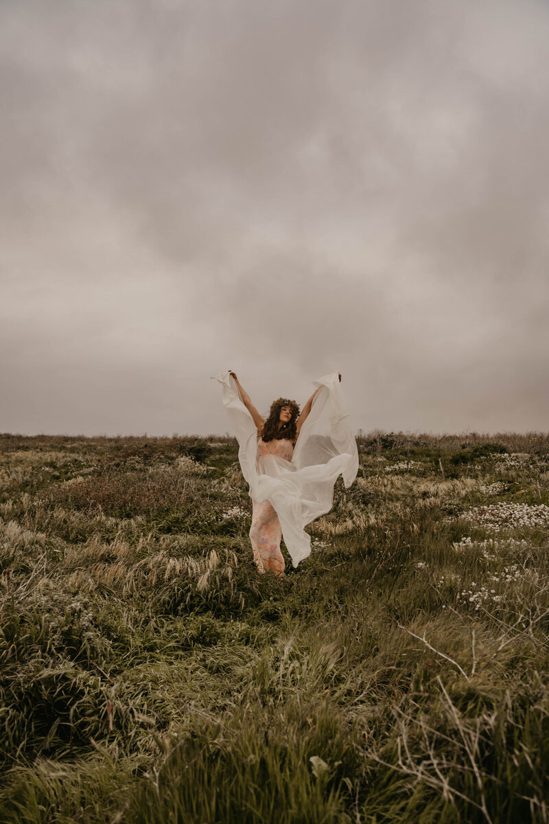 bride lifts dress in field