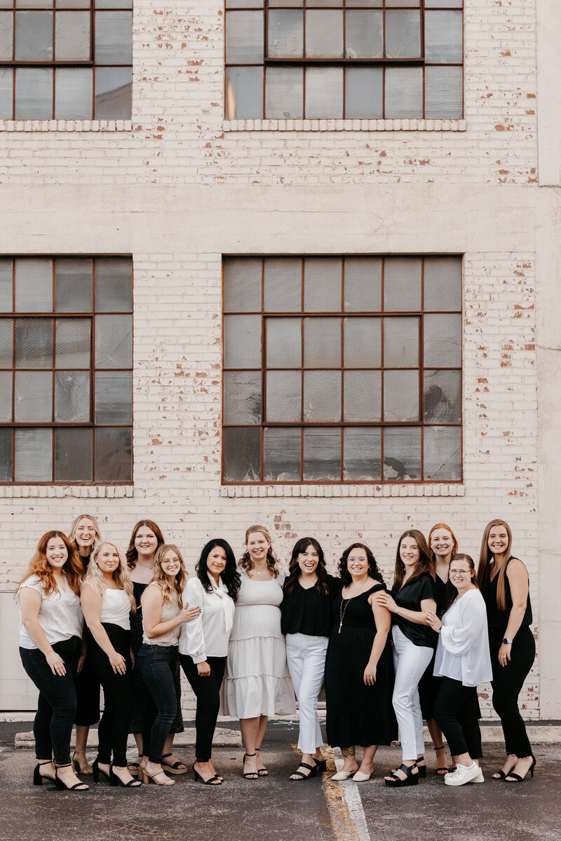 Wedding planners and coordinators who work at radiantly curated pose together and smiling at the camera in black and white clothing