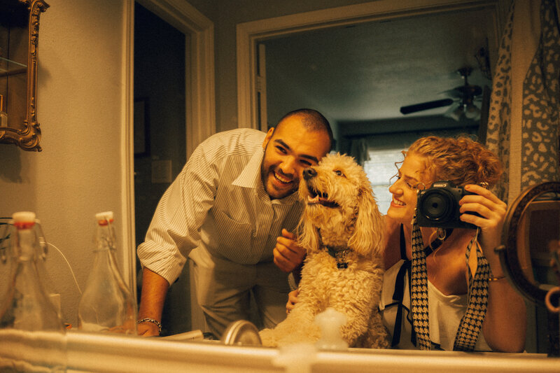A woman and her golden doodle dog pose for a photo outside in the sunlight