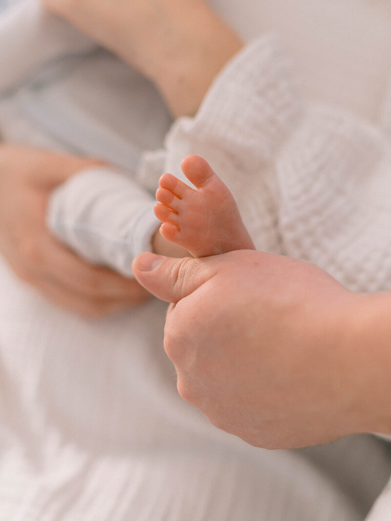 Family of three in a tender moment captured in their home, bathed in gentle natural light by a newborn and family photographer in Sugar House, Utah.