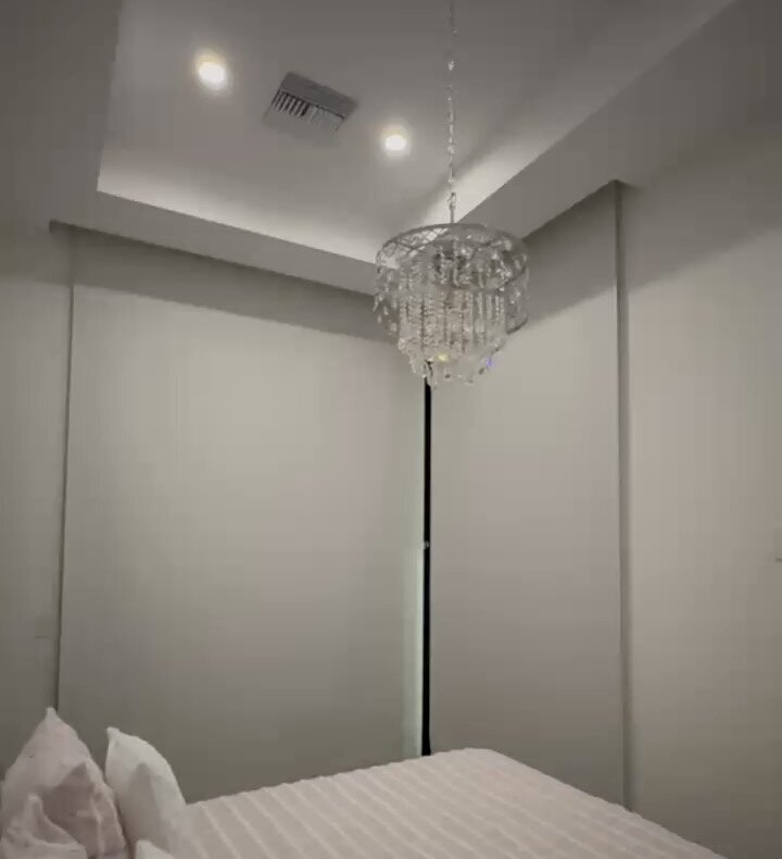 Floor-to-ceiling blackout roller shades closed in a MacDonald Highlands bedroom with a crystal chandelier