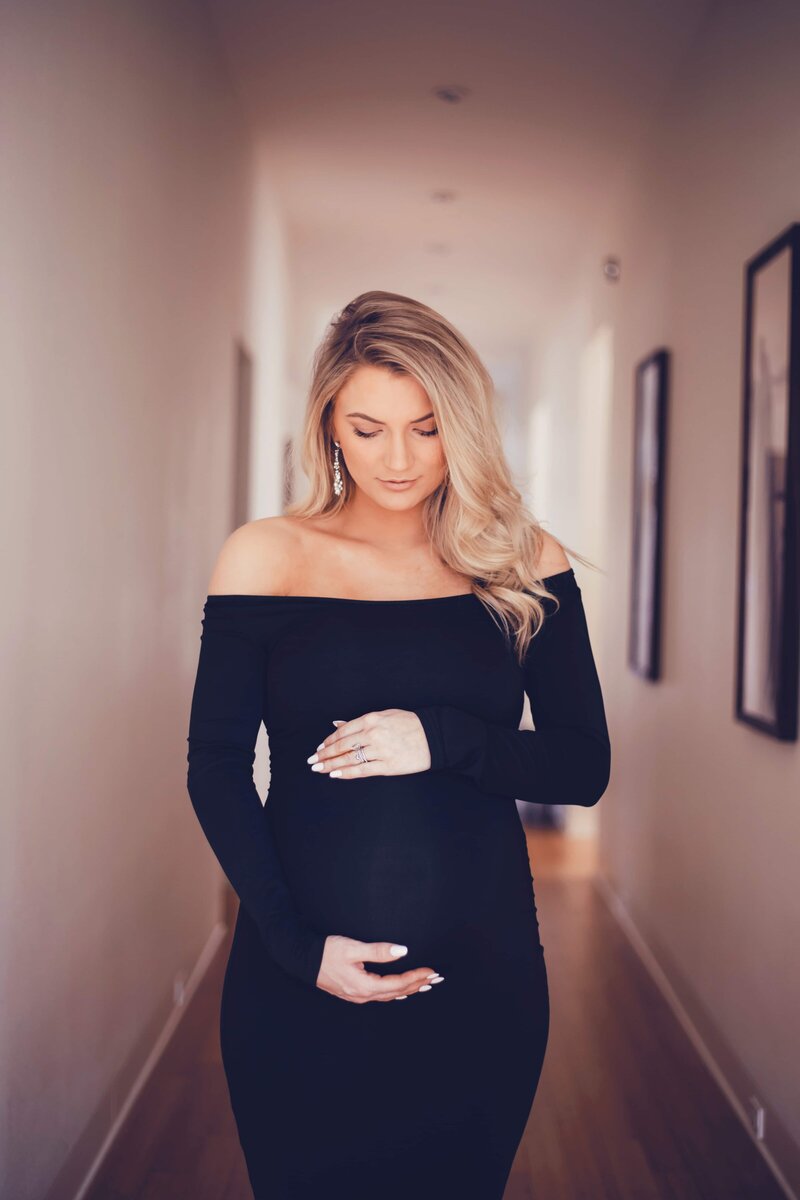 Pregnant woman in a black dress standing in a hallway captured beautifully by Shreveport maternity photographer Britt Elizabeth.