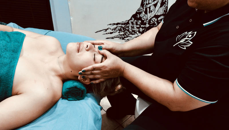 Photo of a relaxed woman's face with eyes closed and massage thearpist's hands on her scalp