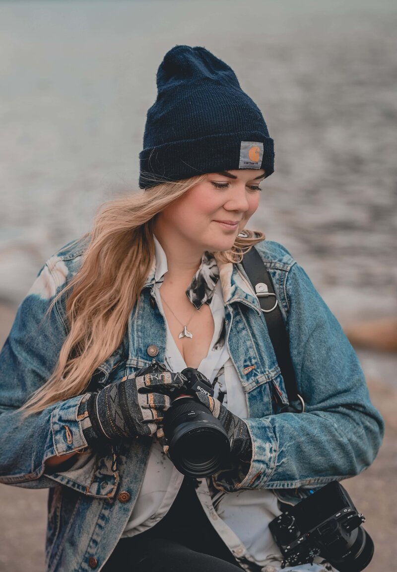 Portrait of Kat Simecek holding her camera in front of a lake