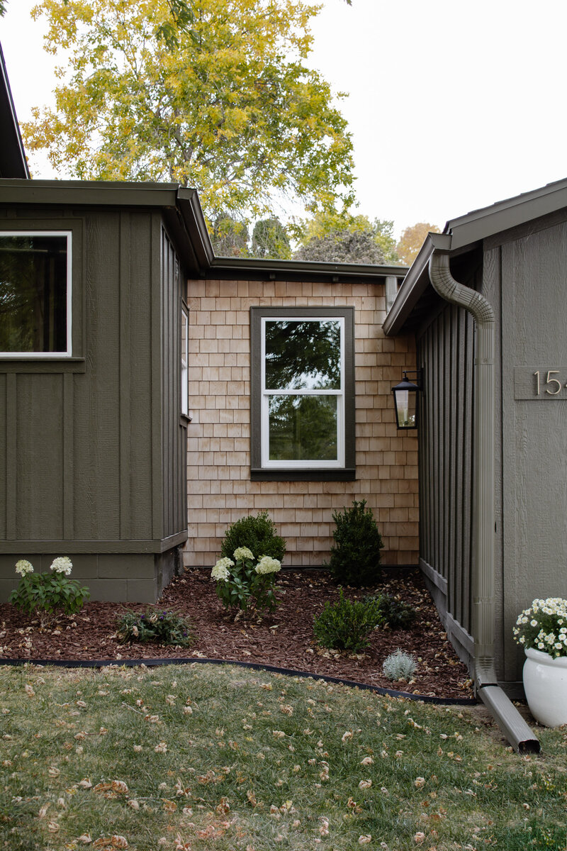 The exterior project by Nadine Stay. Board and batten siding install. Muddled Basil by Sherwin Williams exterior paint color. Flagstone path, brick front porch floor, and a custom built railing. Cabin exterior.