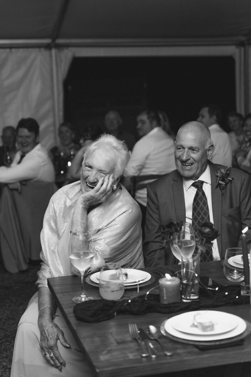 Grandparents of the bride laugh at their wedding speech at the reception. Emotive, authentic photography in Crescent Head, NSW.
