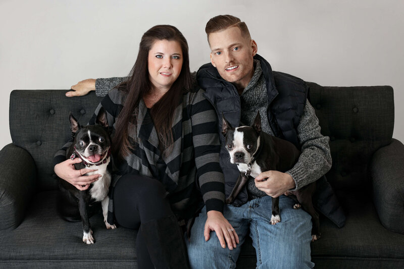 family  photo of a couple sitting on a couch holding two dogs