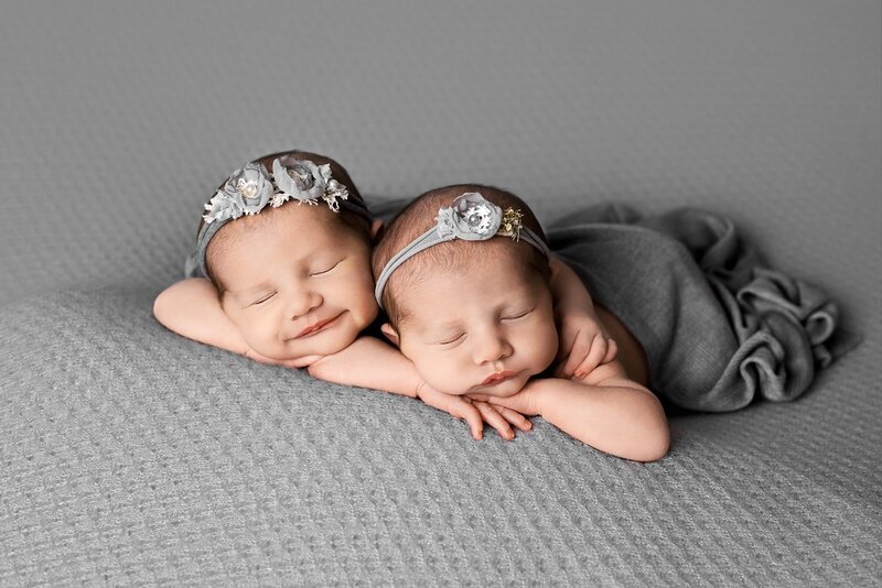In home newborn session in Vancouver with twin girls in grey smiling