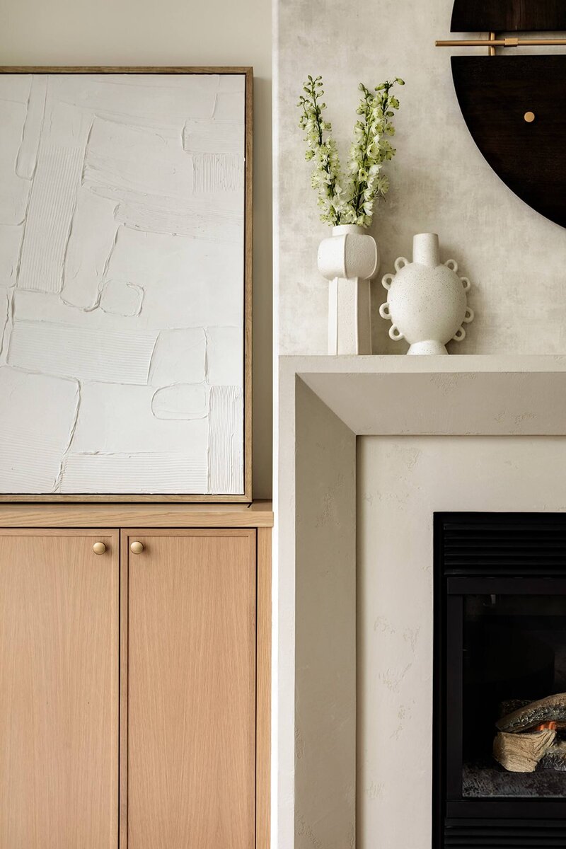 Stone fireplace with wallpaper and white oak cabinets. 