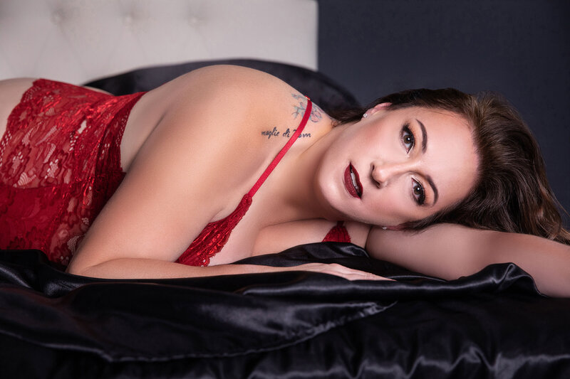Woman in red lingerie laying on black silk sheets in Baton Rouge boudoir studio