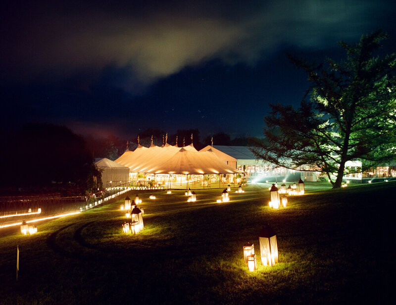 A large tented private estate wedding outside at night lit up with lanterns and lighting