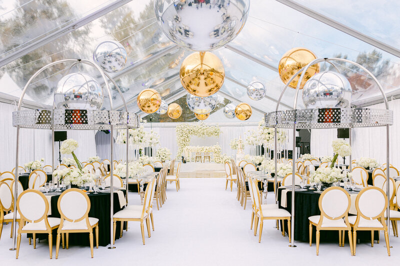 wide shot of black and white wedding reception with white chairs and white florals