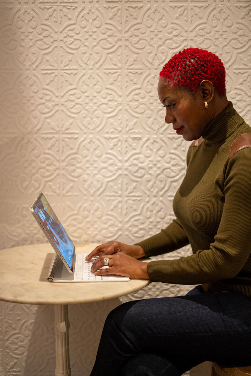 Woman drinking a wine while looking at her laptop
