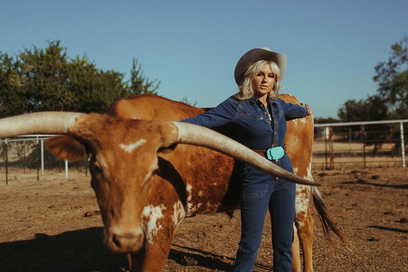 Woman in all denim poses with a cow