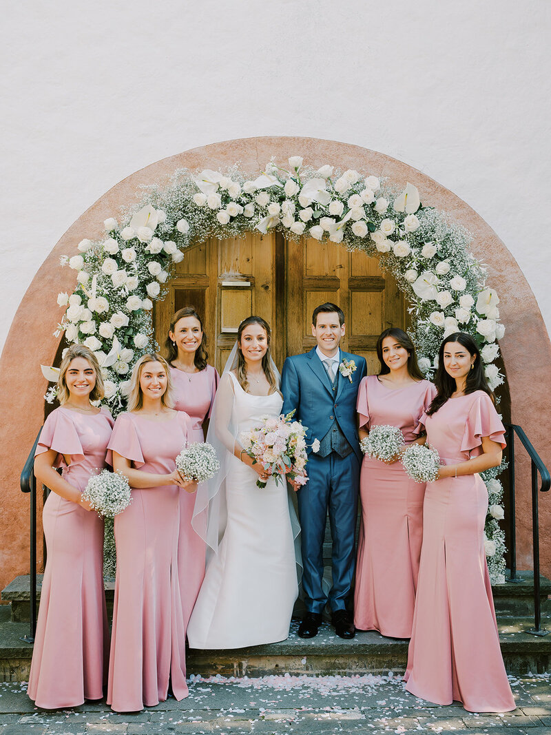 a-bride-and-groom-with-their-witnesses-under-an-arch-of-flowers