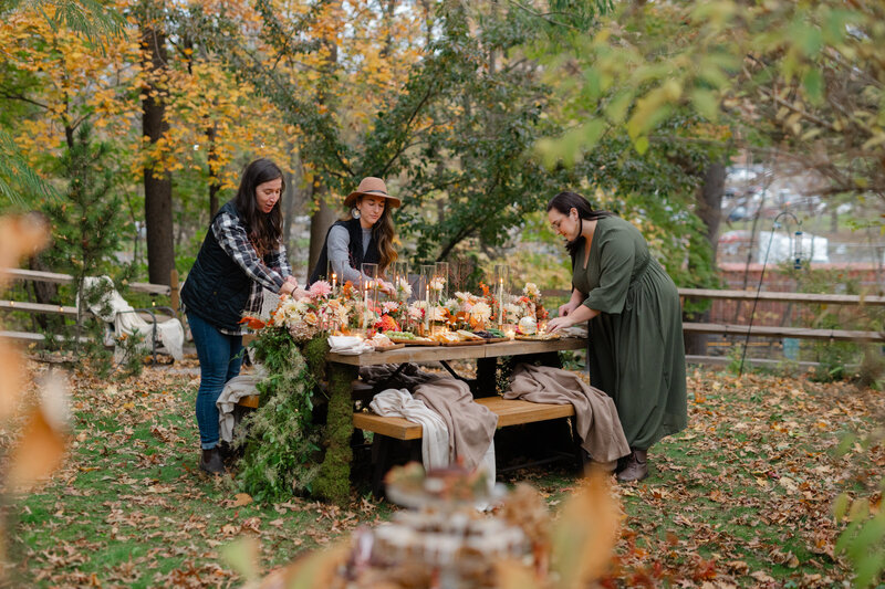 Three people decorating a fall-inspired tablescape