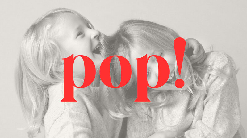 Two young children with long hair are playfully laughing together. The word "pop!" in bold red text overlays the image, adding a playful, joyful tone.
