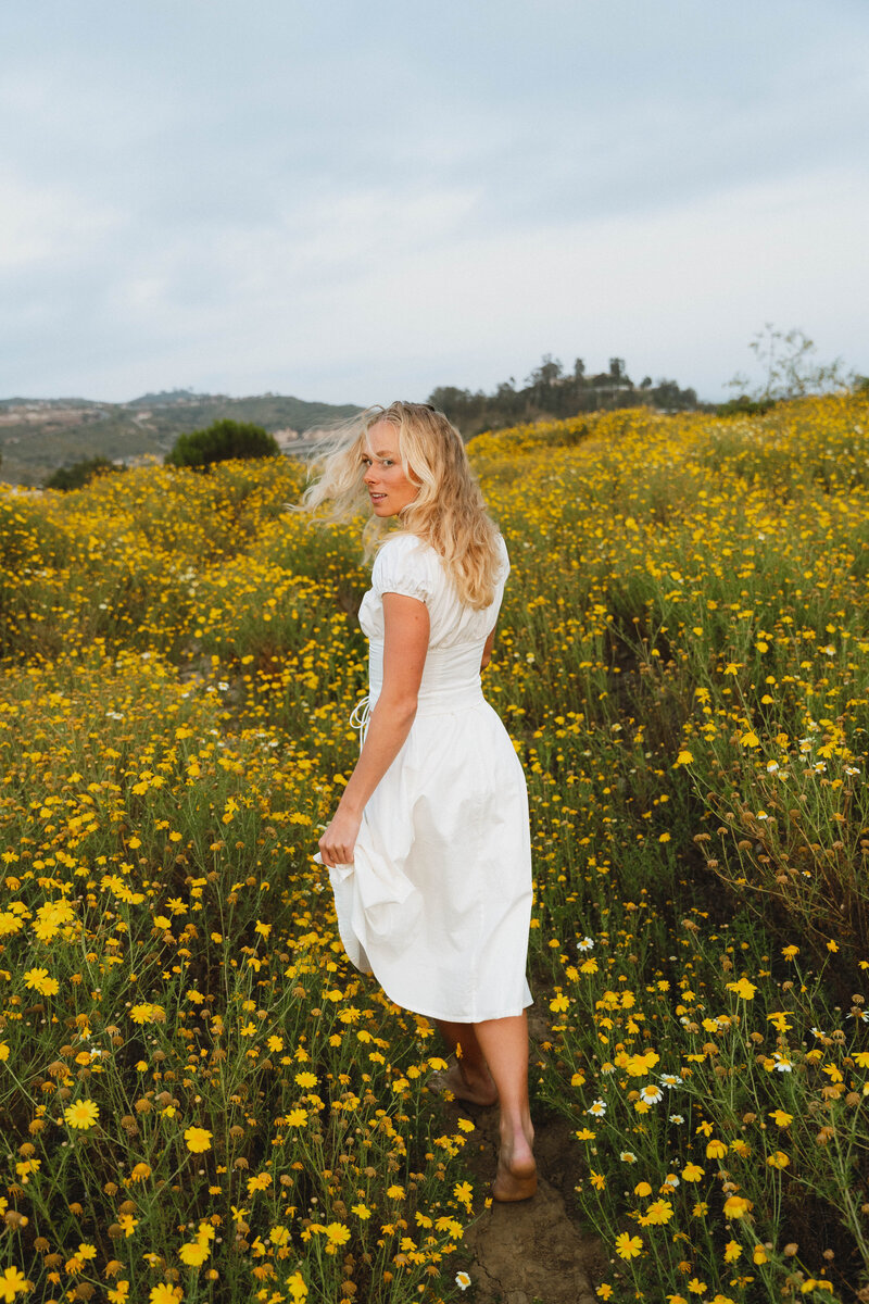 girl walking away in a yellow flower field