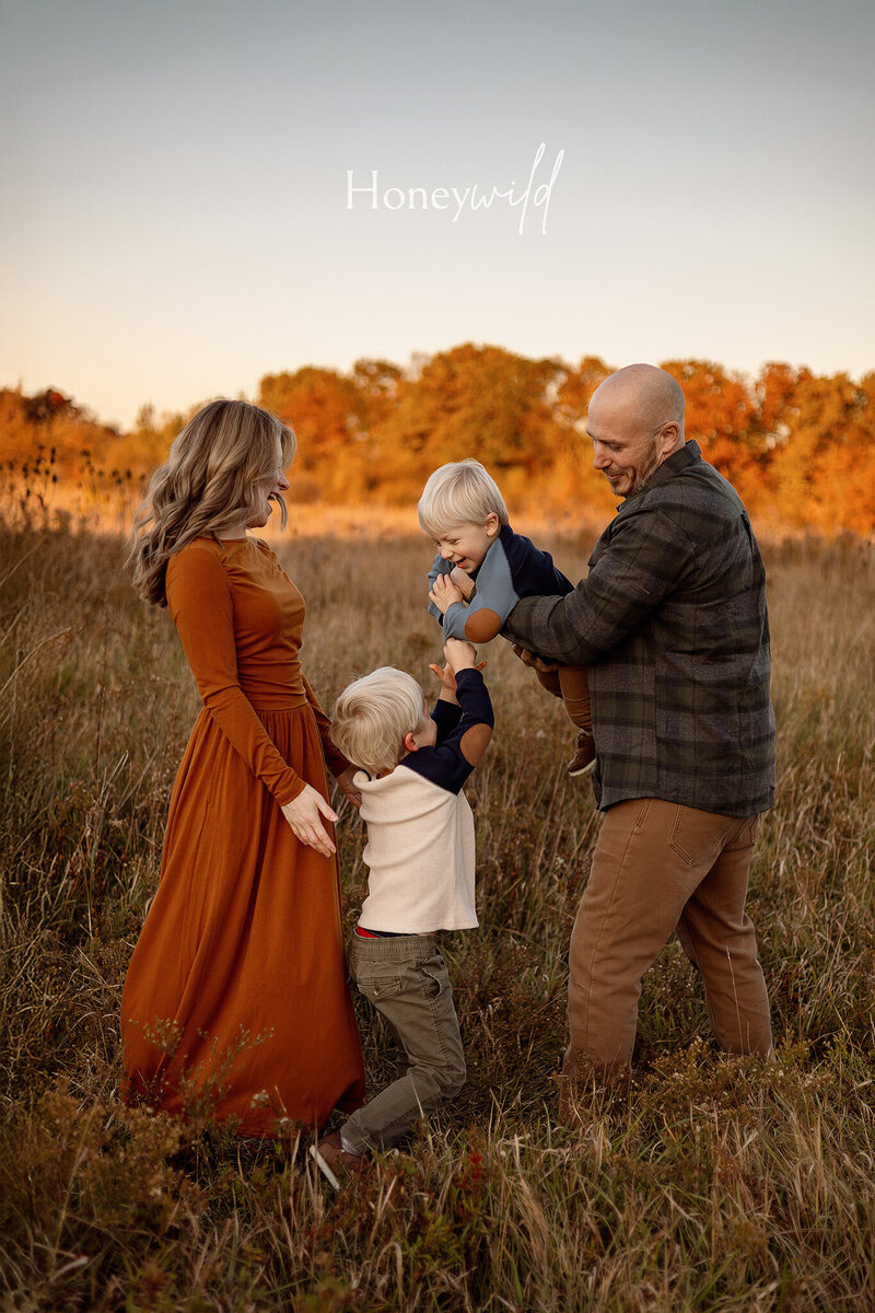 Three young siblings sharing a joyful hug during a golden-hour family photography session in West Michigan, capturing genuine smiles and warm connections