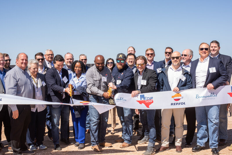 Several people hold a ribbon to cut for the grand opening of a solar farm