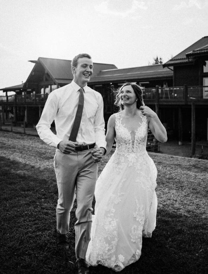 Bride and groom joyfully walking hand in hand captured in black and white.