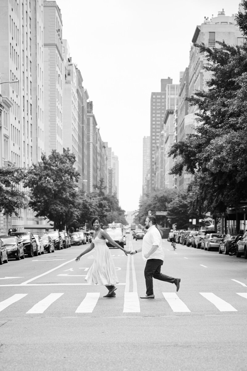 Couple run hand in hand in the streets of NYC during their engagement session. Photo taken by NYC Engagement Photographer Corey Lamar Photography