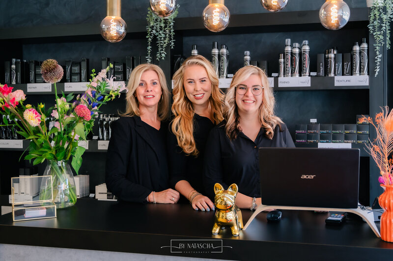 Groepsfoto van de medewerkers van Haarstudio Heesch bij de balie