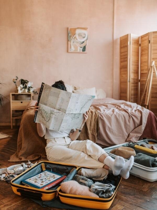 Personne assise au sol avec une carte routière et une valise, illustrant la facilité d’accès à la clinique de Brigitte Vachon à Montréal