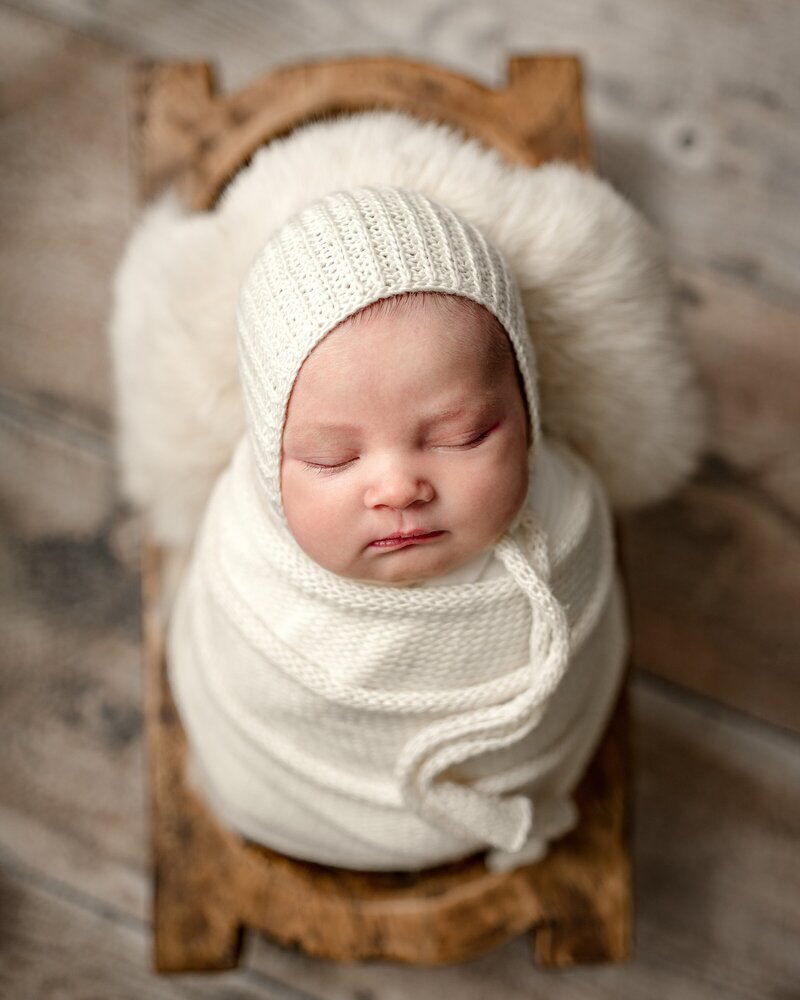 sleeping-newborn-wrapped-in-wood-cradle