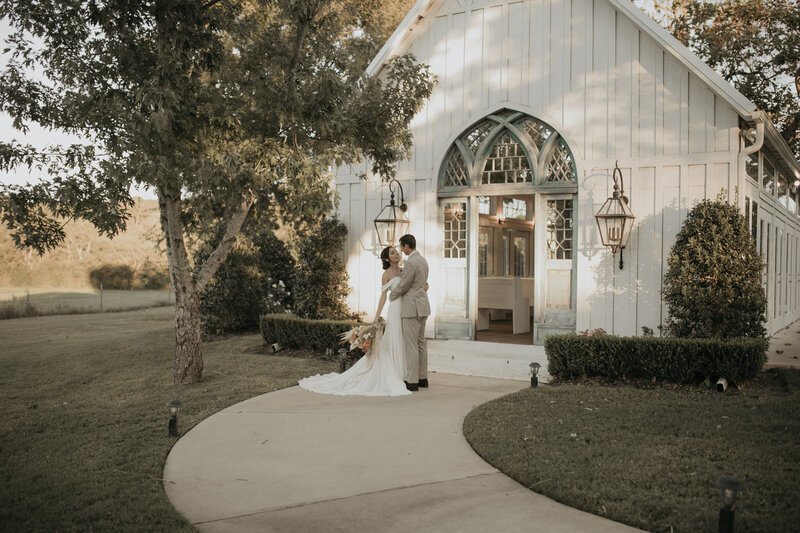 A couple in front of a white wedding chapel in Tyler, Texas