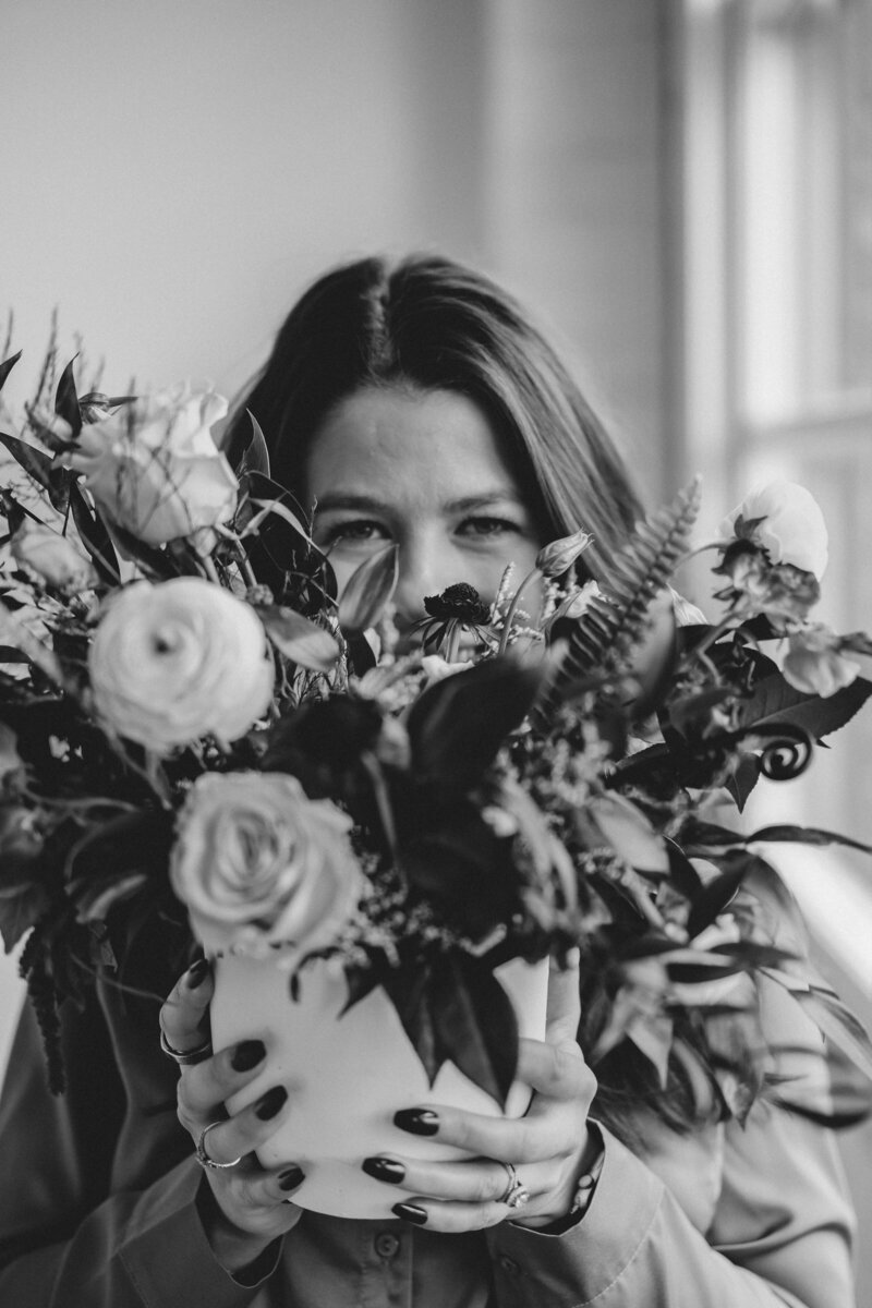 A young woman holds a beautiful bouquet of flowers out in front of her during a branding photo session in Parker, Colorado.