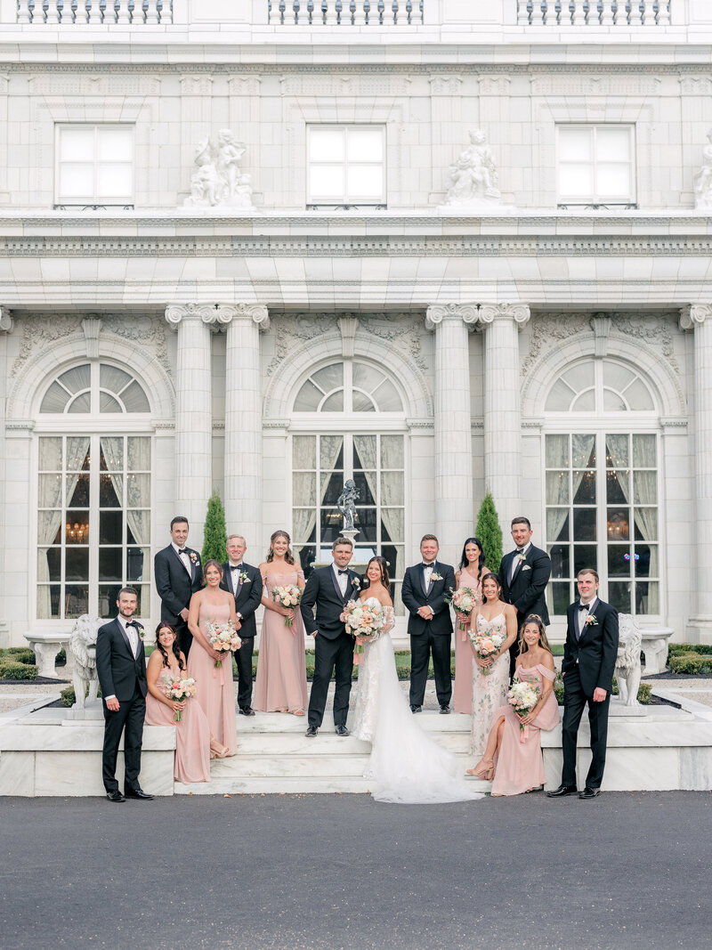Wedding party stand on the steps in front of Rosecliff Mansion