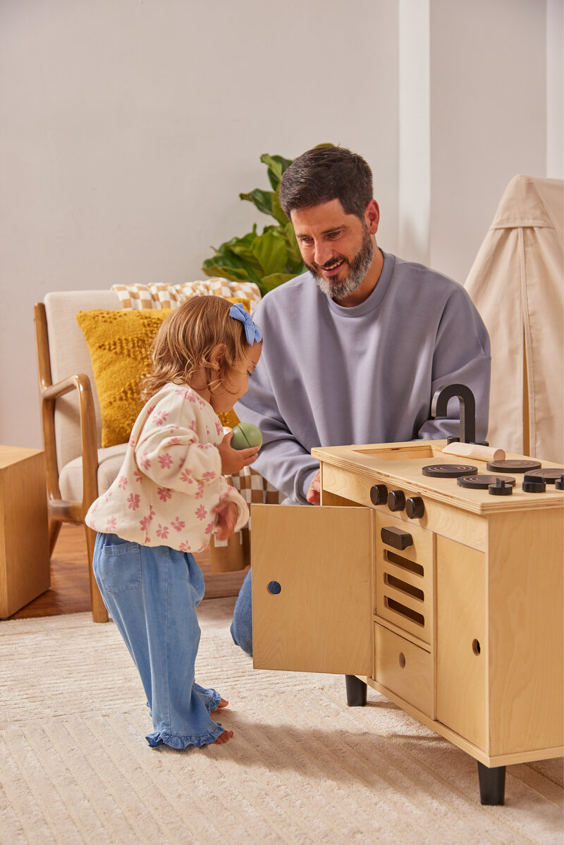 Man playing with toddler at a play kitchen