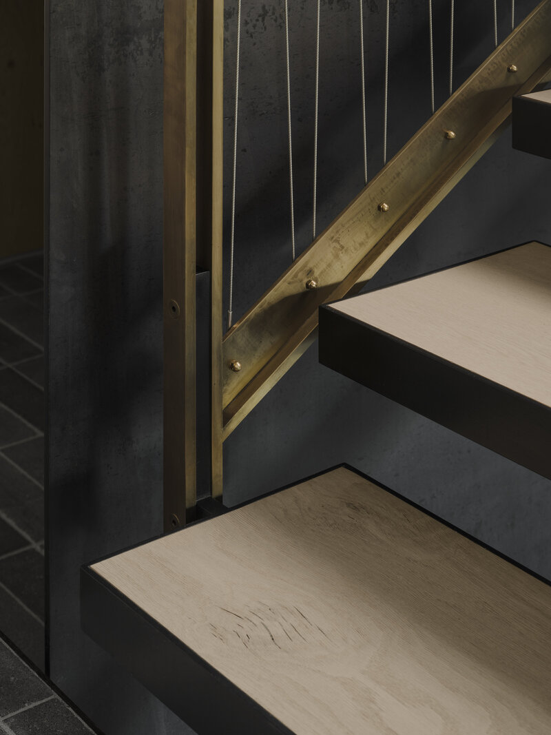Closeup of custom brass and oak wood staircase at modern Whistler cabin.