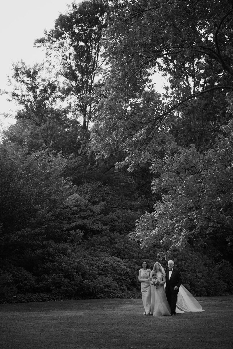 A bride is walked down the aisle by her parents 