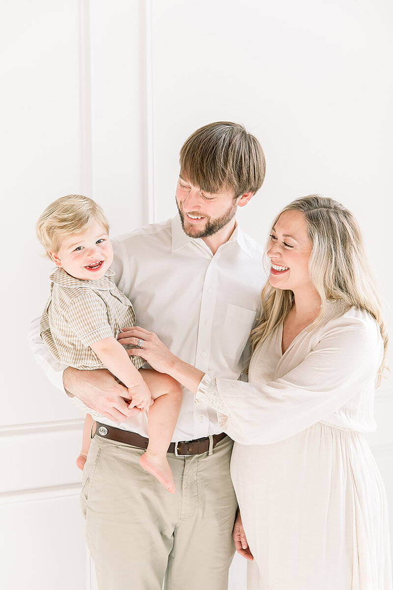 Pregnant mother with husband and toddler son during a bright, neutral-toned studio maternity session.