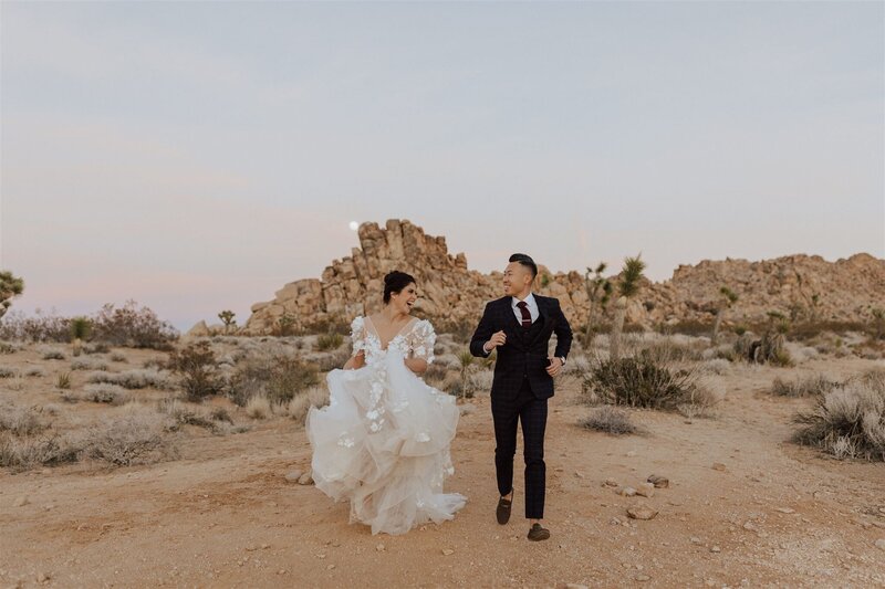 bride and groom running to camera in a desert