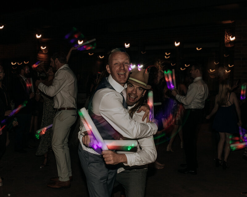 groom hugging best friend and dancing at wedding reception