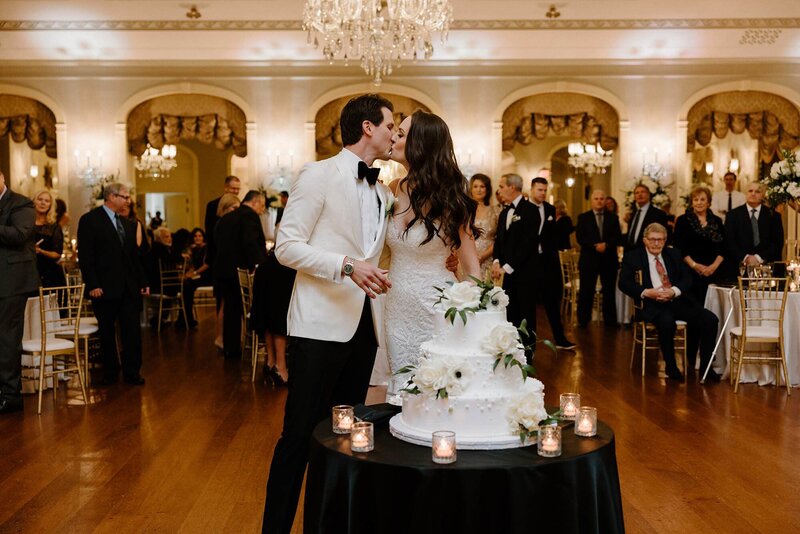 A wedding couple kissing in front of their wedding cake 