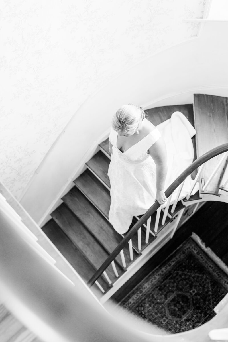 candid black and white of bride walking down stairs at agapae oaks weddings