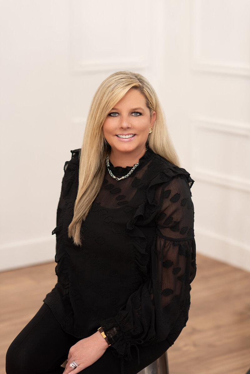 Retouched business headshot of a realtor smiling for the camera in a modern portrait studio