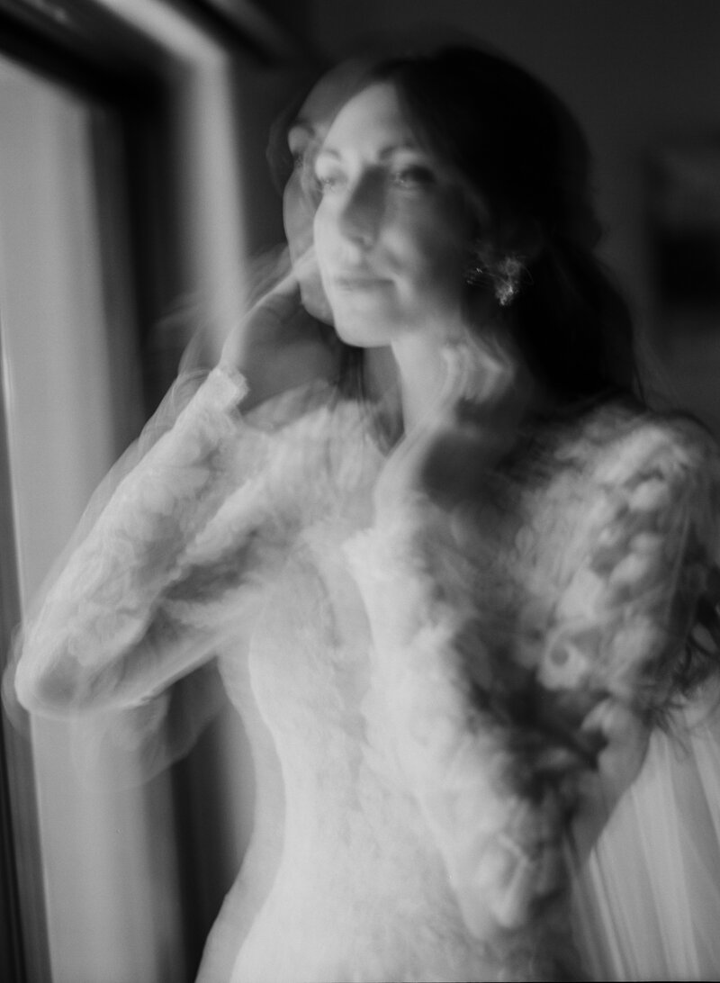 long exposure of bridal portraits as she looks out the window  holding her face
