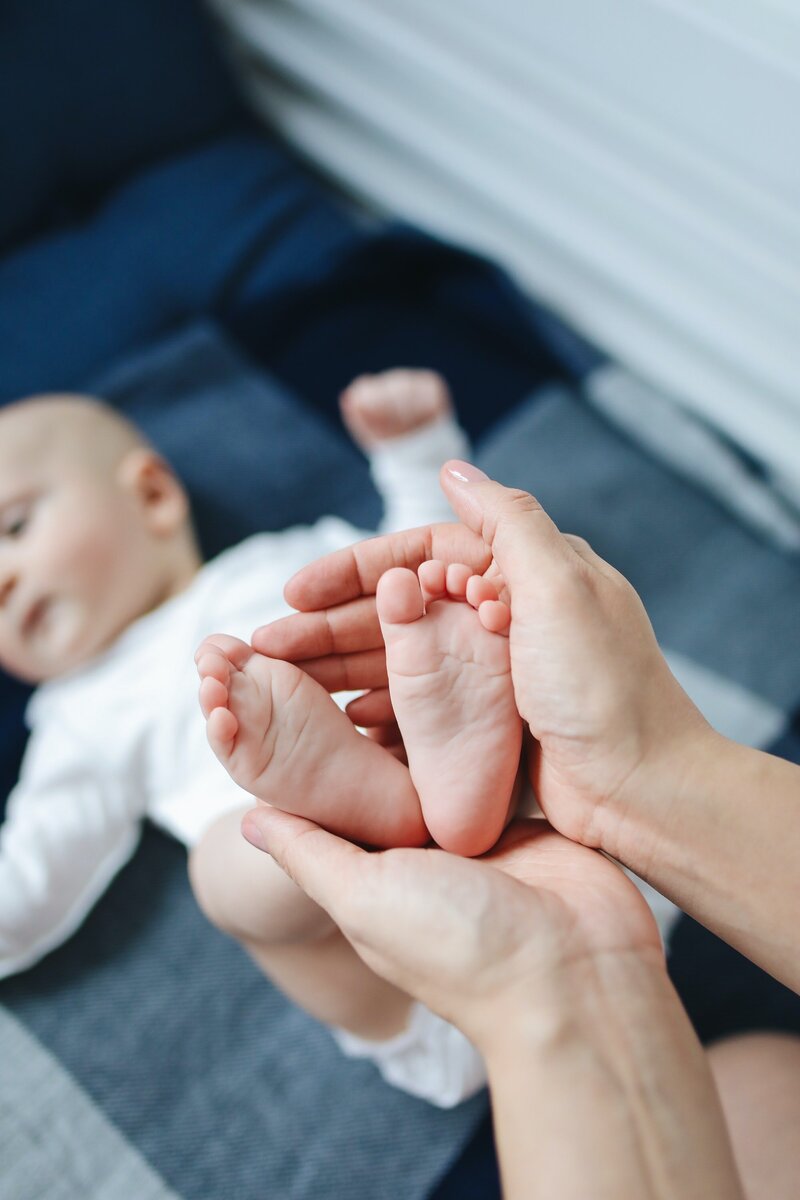 Nanny holding baby feet between their hands
